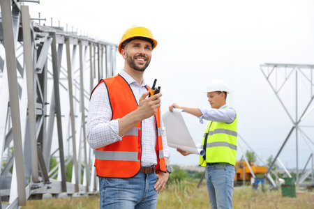 Professional engineers working on installation of electrical substation outdoors