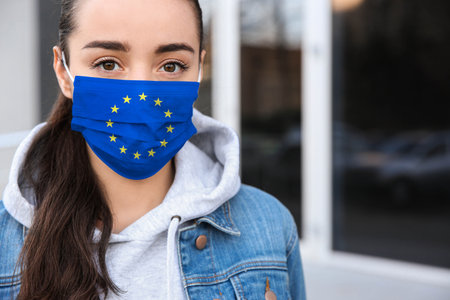 Woman wearing medical mask with European Union flag, outdoors.の写真素材