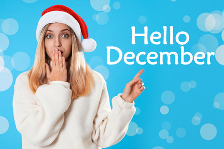 Hello November greeting card. Surprised woman in Santa hat on light blue background, bokeh effectの写真素材