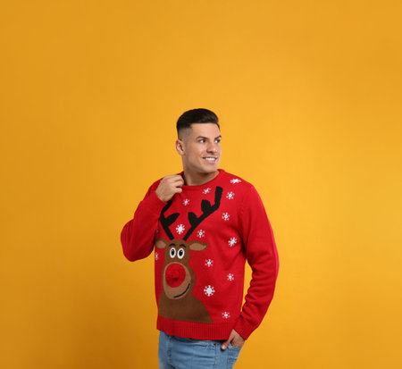 Handsome man in Christmas sweater on yellow backgroundの写真素材