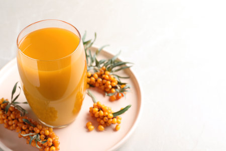 Delicious sea buckthorn juice and fresh berries on light gray marble table, closeup. Space for textの写真素材