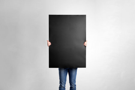 Man holding blank poster on light gray backgroundの写真素材