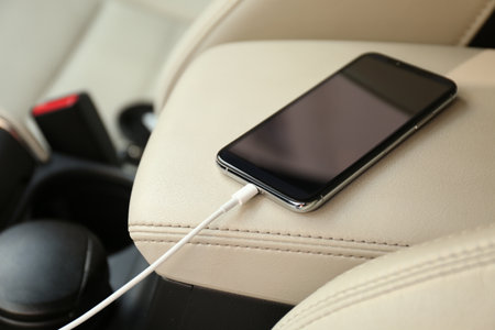 Mobile phone with charging cable in car, closeupの写真素材