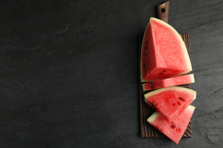 Slices of ripe juicy watermelon on black table, top view. Space for textの写真素材