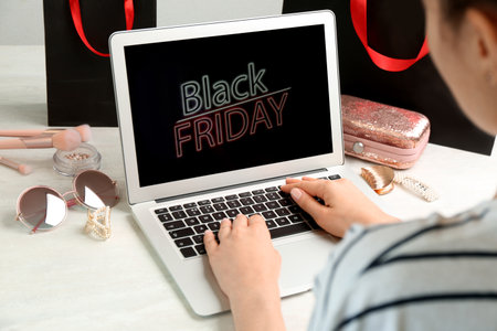 Woman using laptop with Black Friday announcement at white table, closeupの写真素材