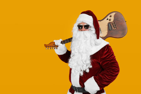 Santa Claus with electric guitar on yellow background, space for text. christmas musicの写真素材