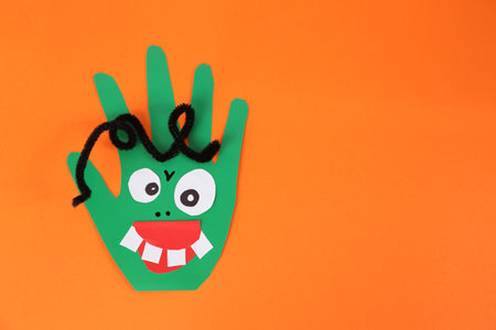 Funny green hand shaped monster on orange background, top view with space for text. halloween decorationの写真素材