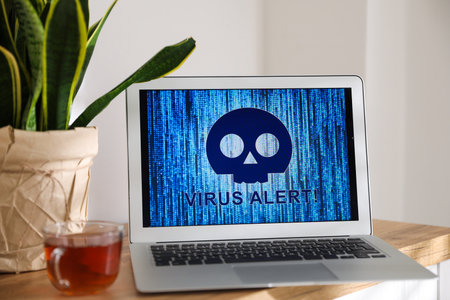 Laptop with warning about virus attack on wooden table indoorsの写真素材
