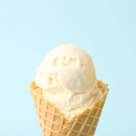 Delicious ice cream in waffle cone on light blue background, closeupの写真素材
