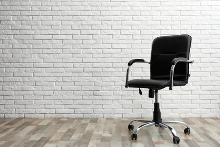 Comfortable office chair near white brick wall indoors. Space for textの写真素材