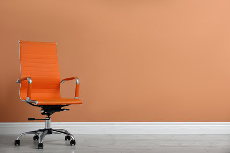 Modern office chair near orange coral wall indoors. Space for textの写真素材