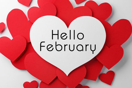 Greeting card with text Hello February. Many red paper hearts and one with text on white background, flat layの写真素材