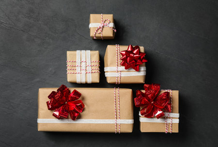 Christmas gift boxes with red bows on dark gray background, flat lay
