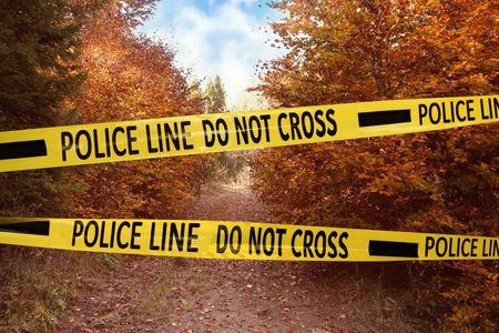Yellow police tape isolating crime scene. Restricted area of autumn parkの写真素材