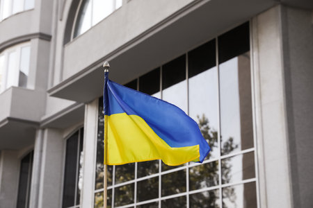 National flag of Ukraine fluttering near building on sunny dayの写真素材