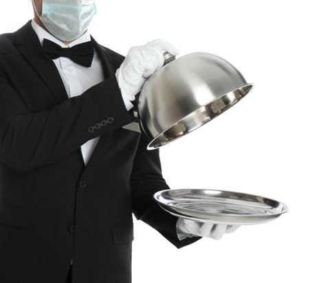 Waiter in medical mask holding tray with lid on white background, closeupの写真素材