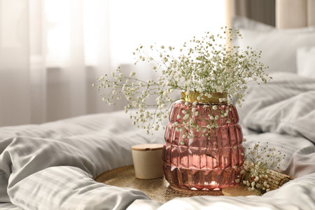 Vase with bouquet of beautiful Gypsophila flowers on bed indoorsの写真素材