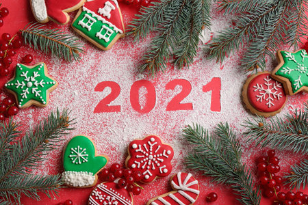 Flat lay composition with number 2021 made of flour and tasty homemade Christmas cookies on red backgroundの写真素材