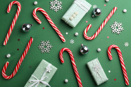 Flat lay composition with candy canes and Christmas decor on green backgroundの写真素材