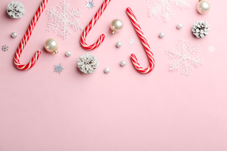 Flat lay composition with candy canes and Christmas decor on pink background. Space for textの写真素材