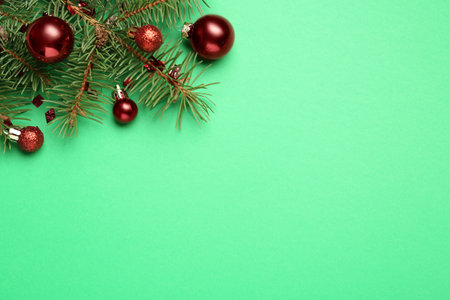 Fir branch with shiny Christmas balls and confetti on green background, flat lay. Space for textの写真素材