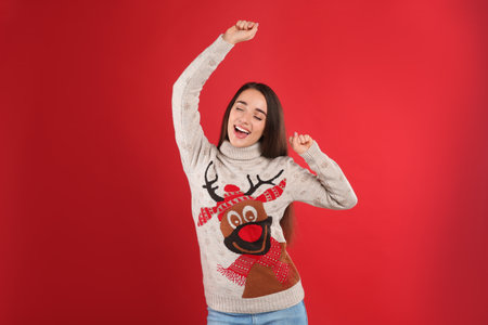 Young woman in Christmas sweater on red backgroundの写真素材