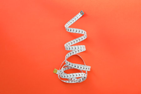 White measuring tape on orange background, top view