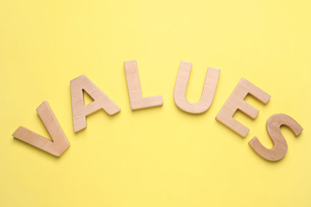 Word VALUES made of wooden letters on yellow background, flat lay