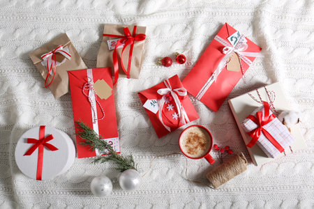 Flat lay composition with Christmas gifts, cup of coffee and festive decor on white knitted fabric. Creating Advent Calendarの写真素材
