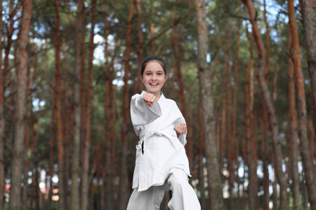 Cute little girl in kimono practicing karate in forestの写真素材