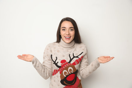 Young woman in Christmas sweater on white backgroundの写真素材