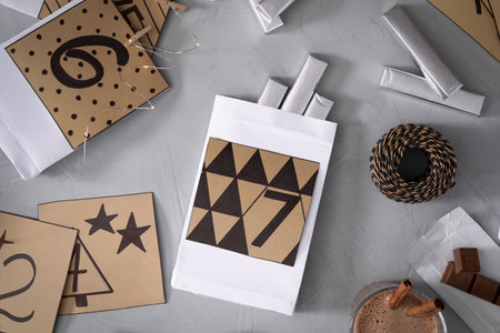 Flat lay composition with gift bags and chocolate on gray table. Creating an advent calendar