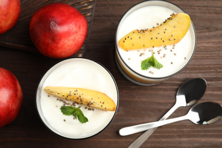 Tasty peach dessert with yogurt and chia seeds served on wooden table, flat layの写真素材