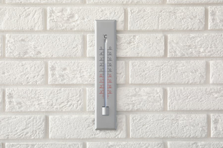 Weather thermometer hanging on white brick wallの写真素材