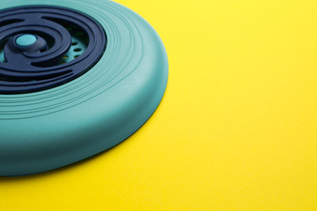 Blue plastic  disk on yellow background, closeup. Space for text