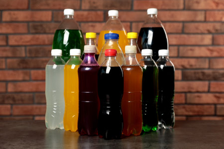 Bottles of soft drinks on table near brick wallの写真素材