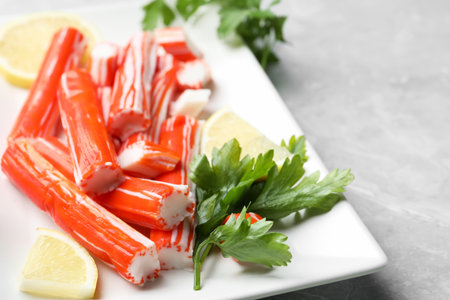 Delicious crab sticks with parsley and lemon on light grey marble table, closeupの写真素材