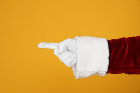 Santa Claus pointing at something on yellow background, closeup of handの写真素材
