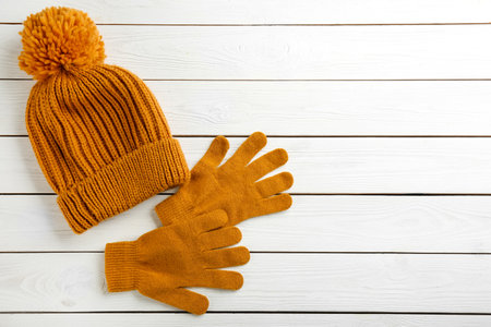 Stylish gloves and hat on white wooden background, flat lay. Space for text