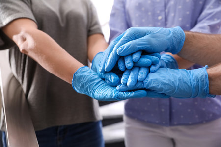 People in blue medical gloves stacking hands on blurred background, closeupの写真素材