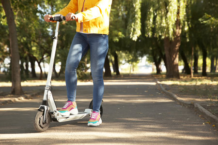 Woman riding electric kick scooter outdoors. Space for textの写真素材