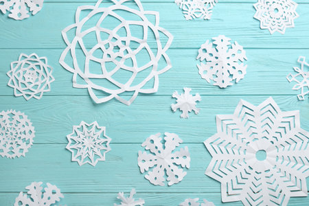 Many paper snowflakes on turquoise wooden background, flat layの写真素材