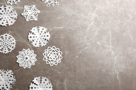 Many paper snowflakes on gray background, flat lay. Space for textの写真素材