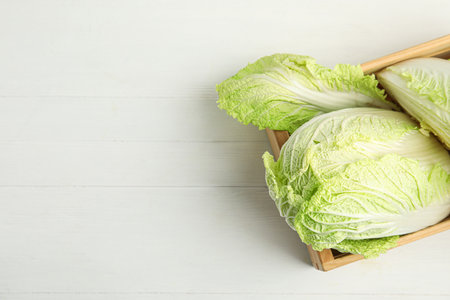Chinese cabbages in wooden crate on white table, top view. Space for textの写真素材