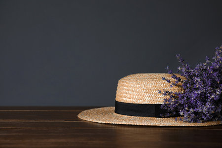 Straw hat and flowers on wooden table. Space for text