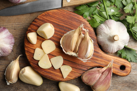 Flat lay composition with fresh sliced and whole garlic on wooden table. organic productの写真素材