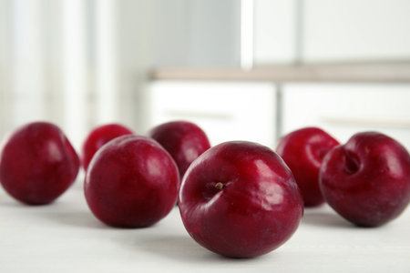 Delicious ripe plums on white wooden table, closeup. Space for textの写真素材