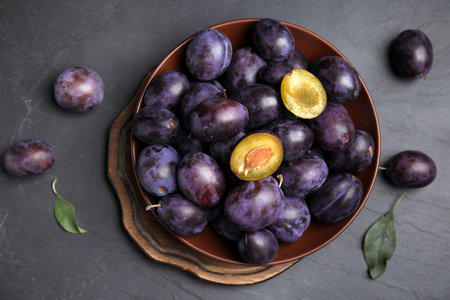 Delicious ripe plums on black table, flat layの写真素材
