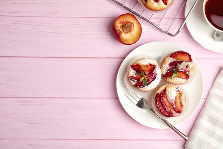Delicious cupcakes with plums on pink wooden table, flat lay. Space for textの写真素材