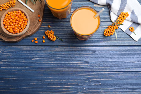 Flat lay composition with sea buckthorn juice on blue wooden table, space for textの写真素材